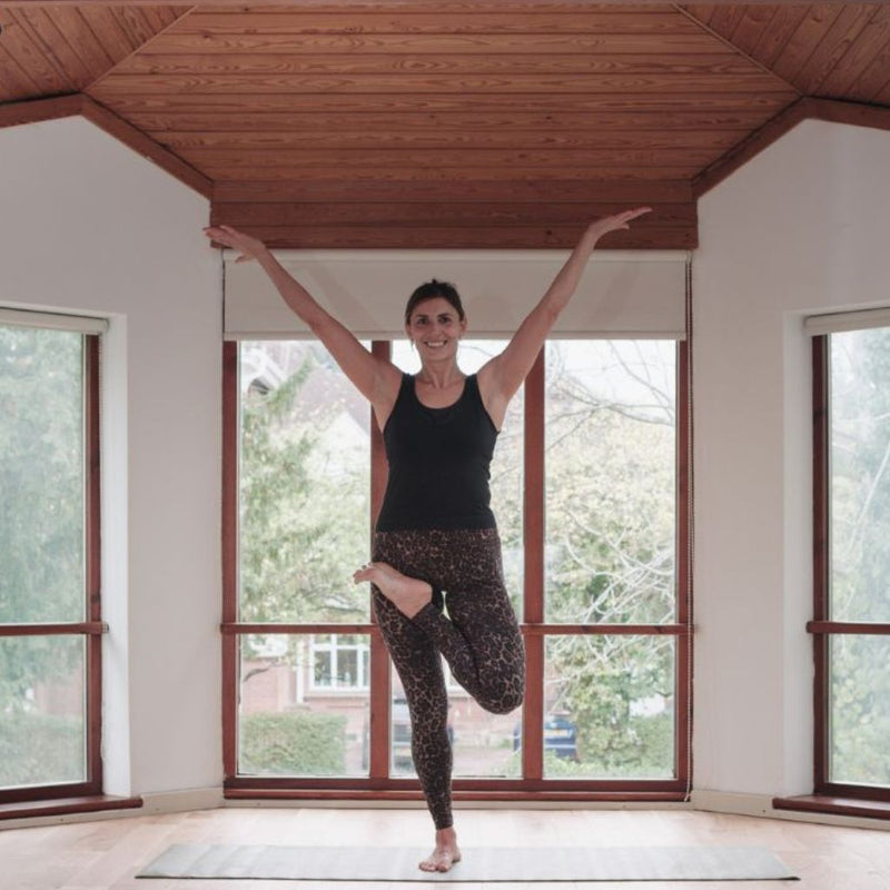 Full body picture of a lady standing on one leg in a yoga pose
