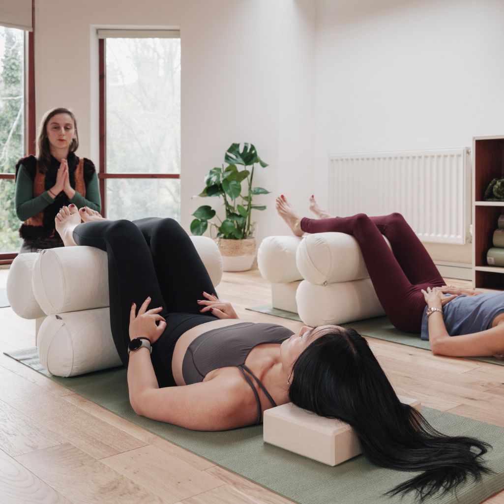 Group of people in a yoga class with a instructor in a bright room.