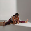 Woman in a yoga pose on a white floor with a neutral background
